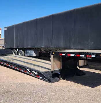 Black flatbed trailer with drop deck.