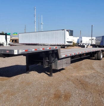 Flatbed semi trailer parked in a gravel lot