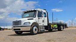 White flatbed tow truck parked outdoors.